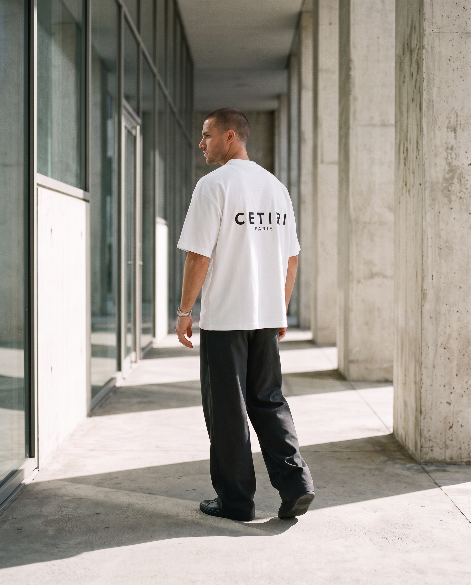 Male model wearing the white CETIRI T-shirt with relaxed wide-leg charcoal trousers
